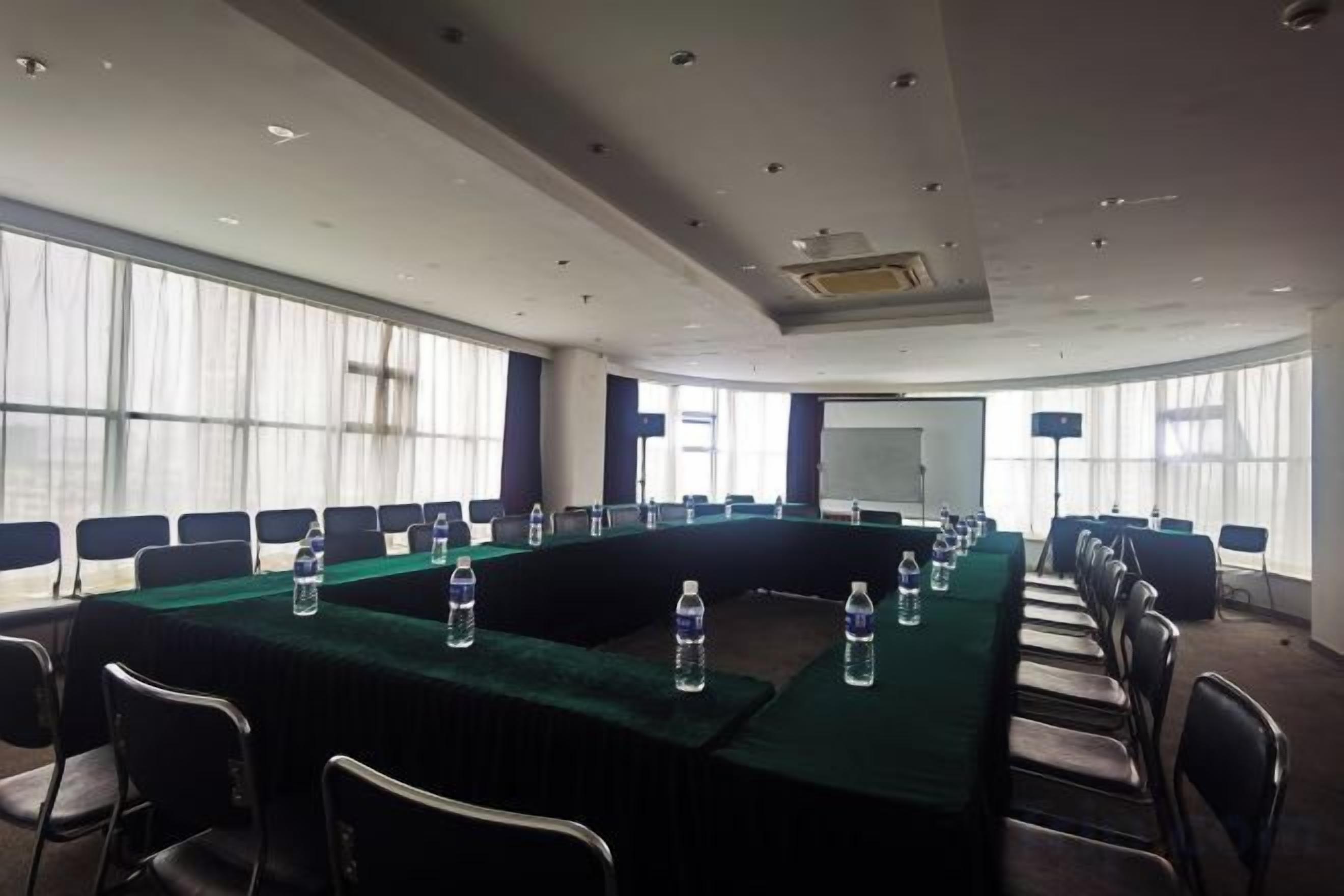 Une salle de conférence avec une longue table, des chaises et des bouteilles d’eau.