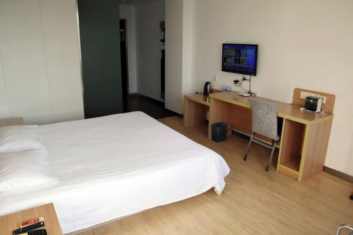 Ein Hotelzimmer mit einem Bett, einem Schreibtisch mit Computer, einem Fernseher und einem Sessel.