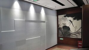 Ein modernes Interieur mit einer gefliesten Wand, Holzboden und einem großen Gemälde von Vögeln auf einem Ast.