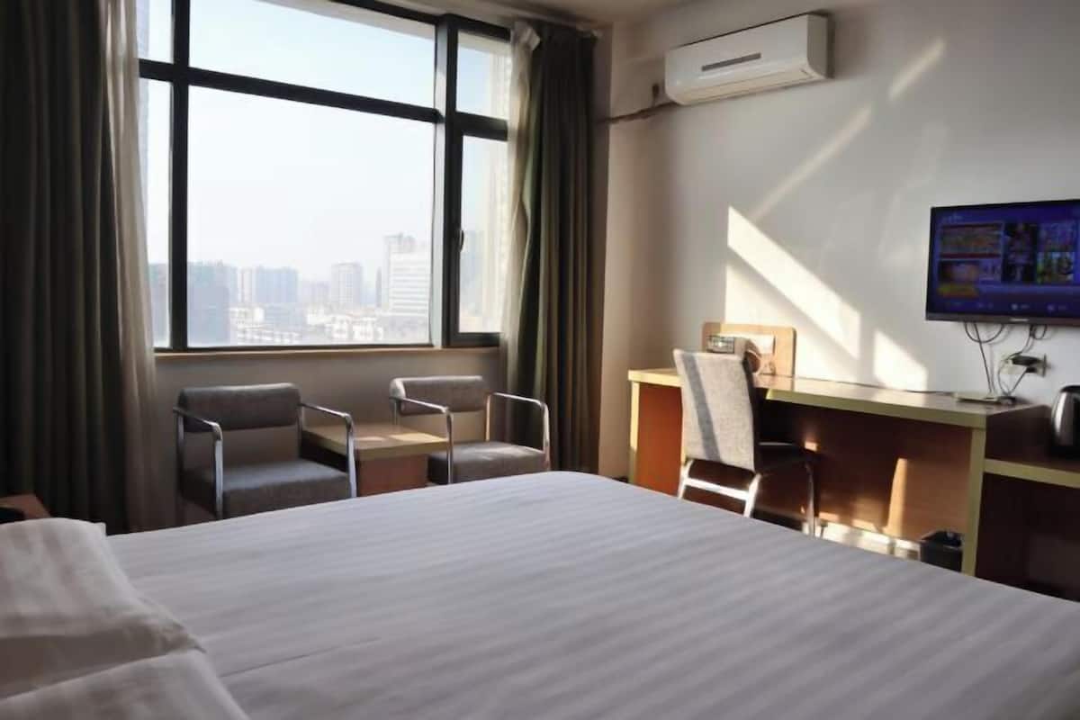 A hotel room with a large bed, two chairs, a desk, and a TV.