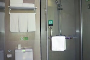 Ein Badezimmer mit Toilette, Handtuchhalter, Dusche mit Glastür und Zugknopf.