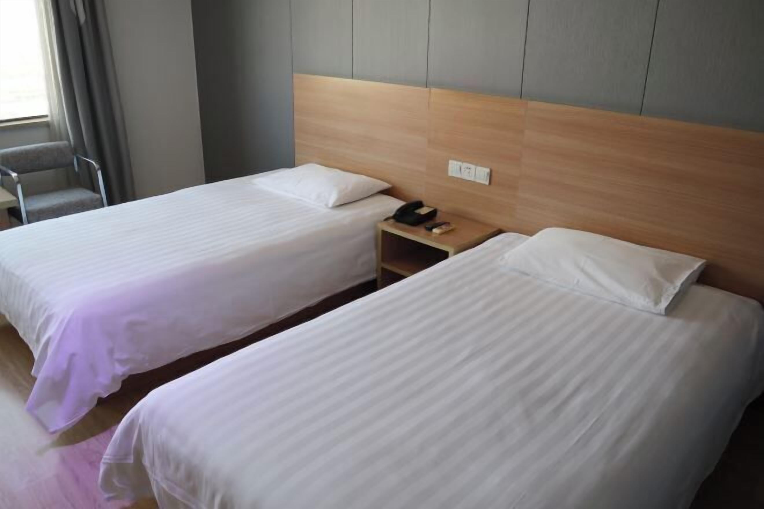 Two single beds with wooden headboards in a hotel room.