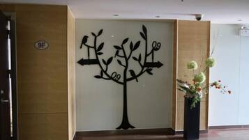 A reception area with a wall-mounted tree decoration, a potted plant, and a sign indicating room 9F.