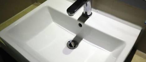 Uma pia de banheiro branca com uma torneira preta e um ralo.