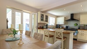 Una cocina moderna con armarios blancos, una isla central y una zona de comedor con mesa y sillas.