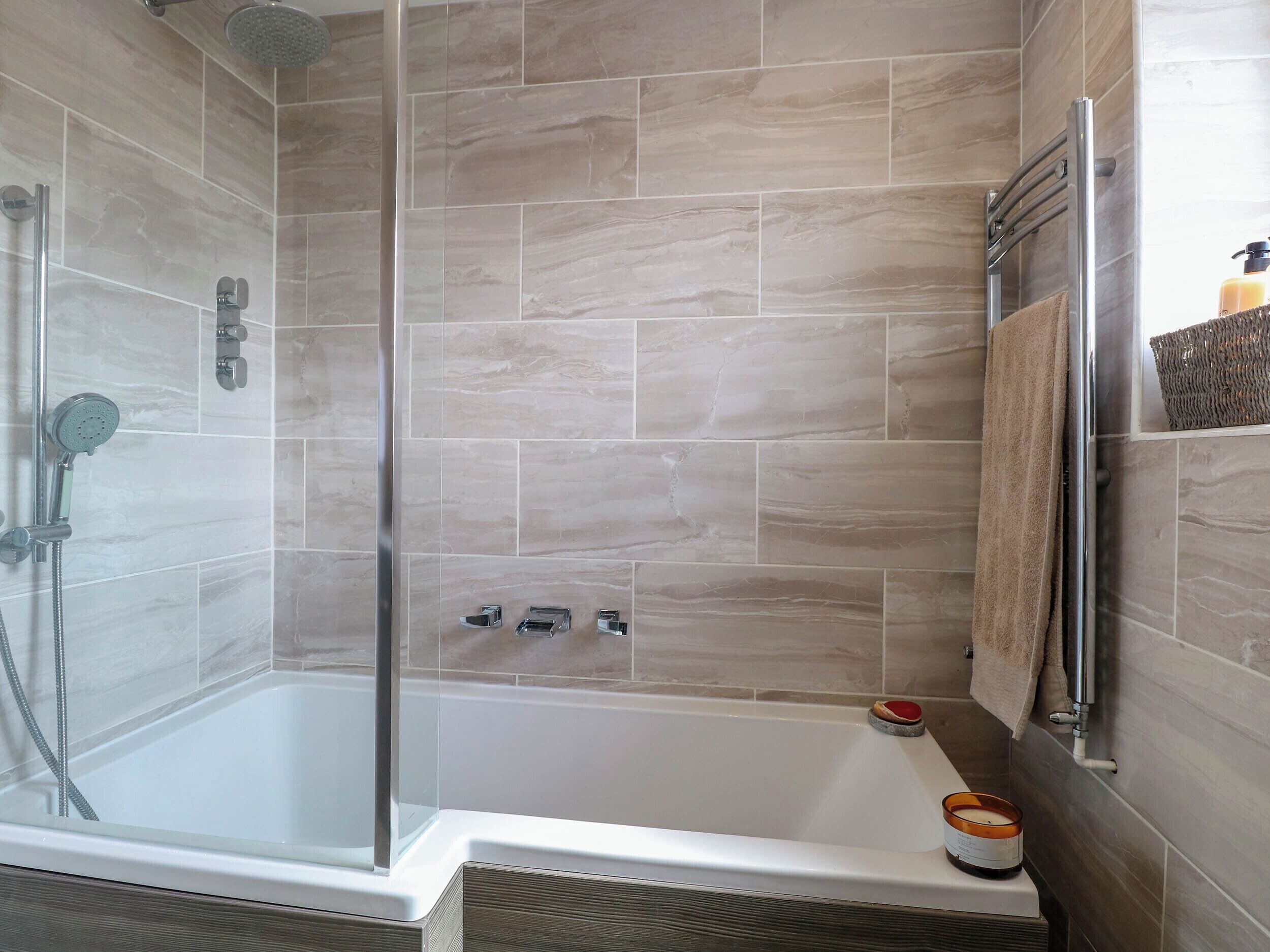 A modern shower area with a glass door, a handheld showerhead, and a wall-mounted faucet.