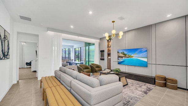 A modern living room with a sectional sofa, a coffee table, and a TV mounted on the wall. - Last Minute Disney! Private Pool, Hot Tub & Themed Bedrooms. Book Now! #124375 (Orlando)
