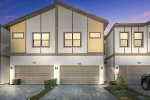 A two-story residential building with a symmetrical facade, large garage doors, and a well-maintained driveway. - Last Minute Disney Getaway! Private Pool & Game Room. Book Now! #119729 (Orlando)
