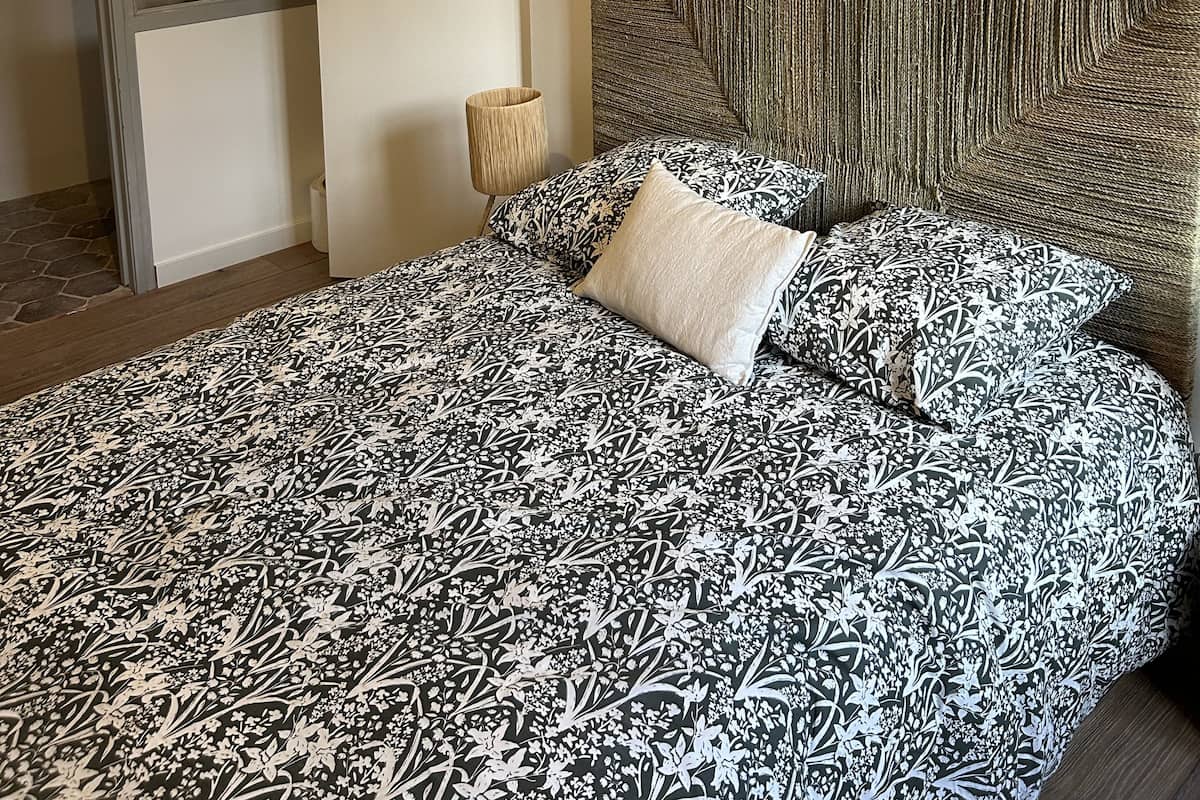 Une chambre à coucher avec un lit, une tête de lit, une porte et une lampe.