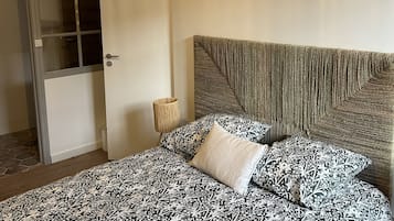 Ein Schlafzimmer mit einem Bett, einem Kopfteil, einer Tür und einer Lampe.