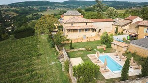 Eine Villa mit Swimmingpool, umgeben von Garten und Weinberg.