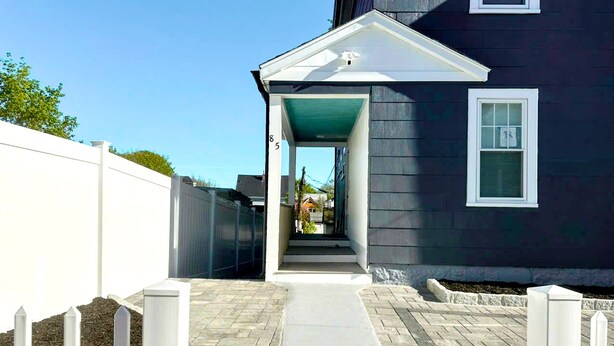 A house with a covered porch, a white picket fence, and a paved walkway leading to the entrance. - 85a Charming, Cozy 3BR, 2BA Home Near Downtown Boston (Boston)