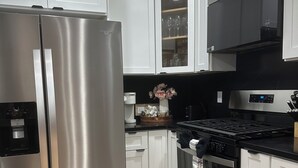 A modern kitchen with stainless steel appliances, white cabinetry, and a wooden floor. - 85a Charming, Cozy 3BR, 2BA Home Near Downtown Boston (Boston)