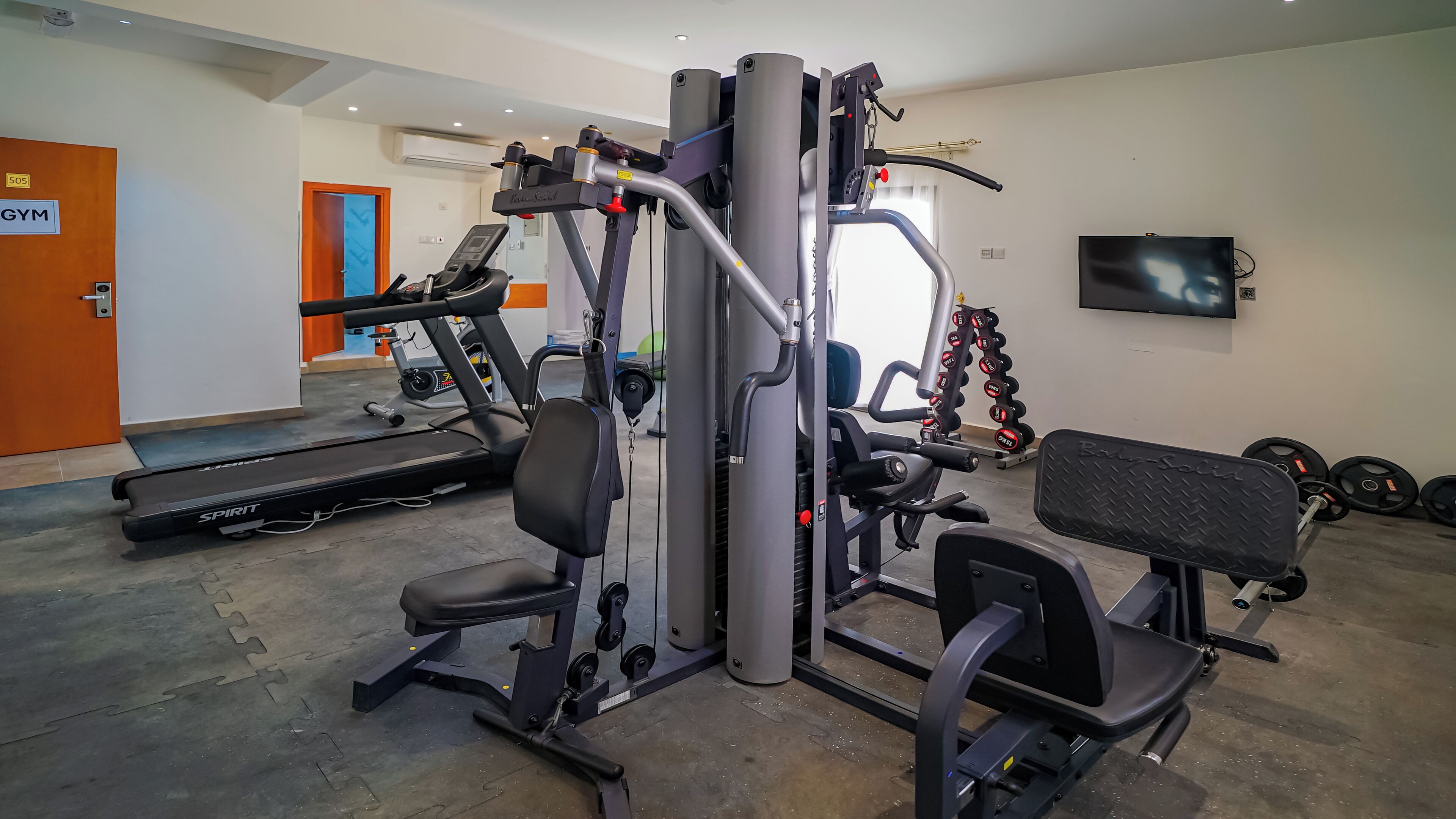 Un gimnasio con equipamiento de ejercicio, una cinta de correr y una banca.