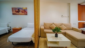 A hotel room with a bed, a sofa, a coffee table, and a painting on the wall.