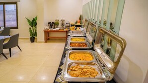A buffet setup with various food items and a coffee station.