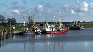 Een rustige haven met drie vissersboten die aan een steiger liggen.