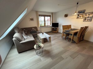 A modern living room with a sofa, coffee table, dining table, and chairs. - Marike Apartment: Quiet Yet Central. Ideal for bike tours (Hage)