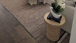 Una sala de estar moderna con un ventanal grande, un sofá, dos sillones, una mesa de centro y una alfombra.