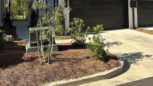 Una casa moderna de dos pisos con un amplio garaje, un camino de entrada bien cuidado y un jardín delantero ajardinado.