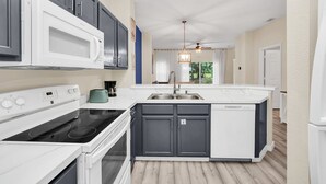 A modern kitchen with a white stove, black oven, and a built-in microwave. - Last Minute Disney Getaway! Private Pool & Themed Bedrooms. Book Now! #121909 (Orlando)