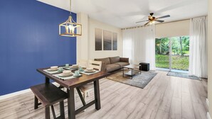 A modern living room with a dining area, a sofa, a ceiling fan, and a view of the outdoors. - Last Minute Disney Getaway! Private Pool & Themed Bedrooms. Book Now! #121909 (Orlando)