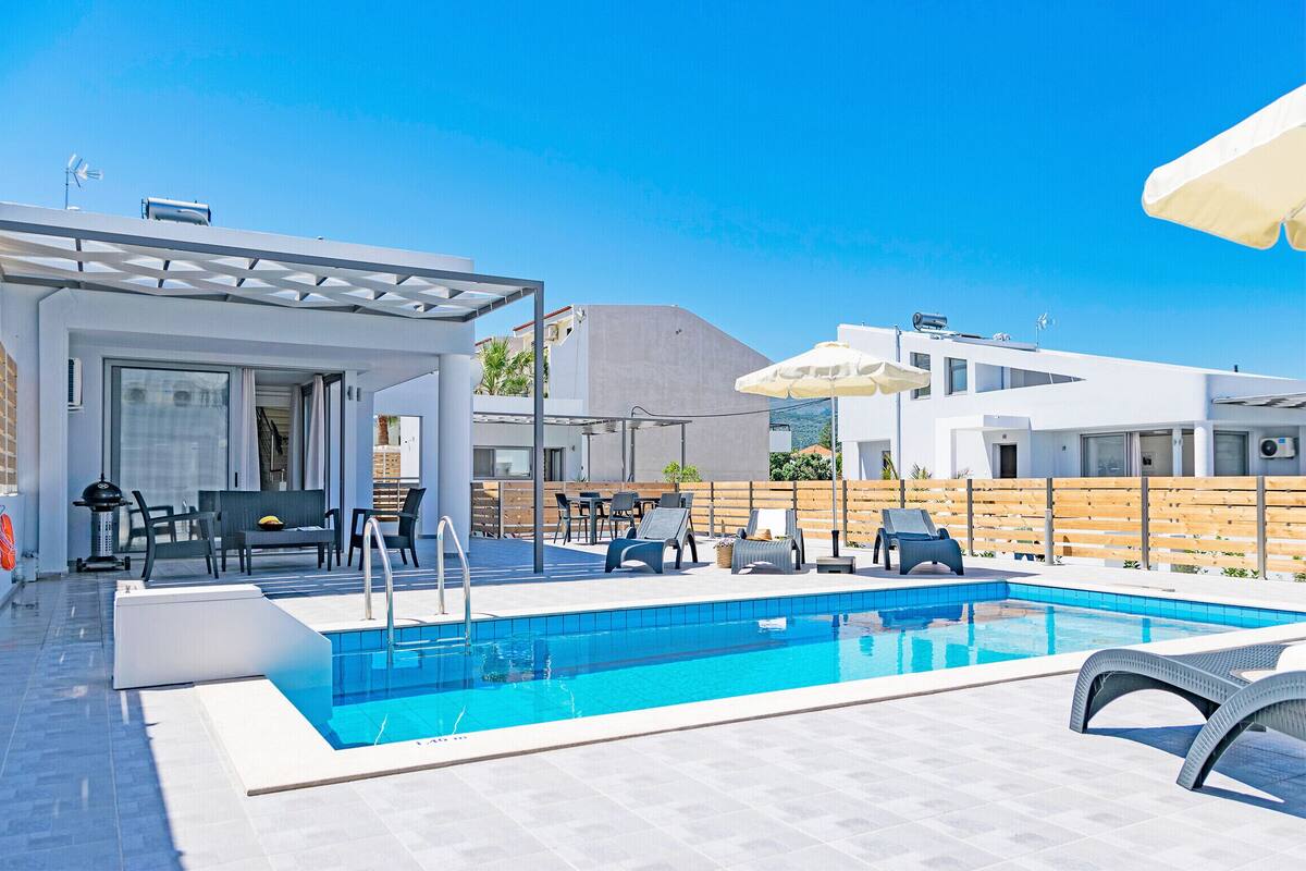 A modern outdoor pool area with lounge chairs and a covered seating area.