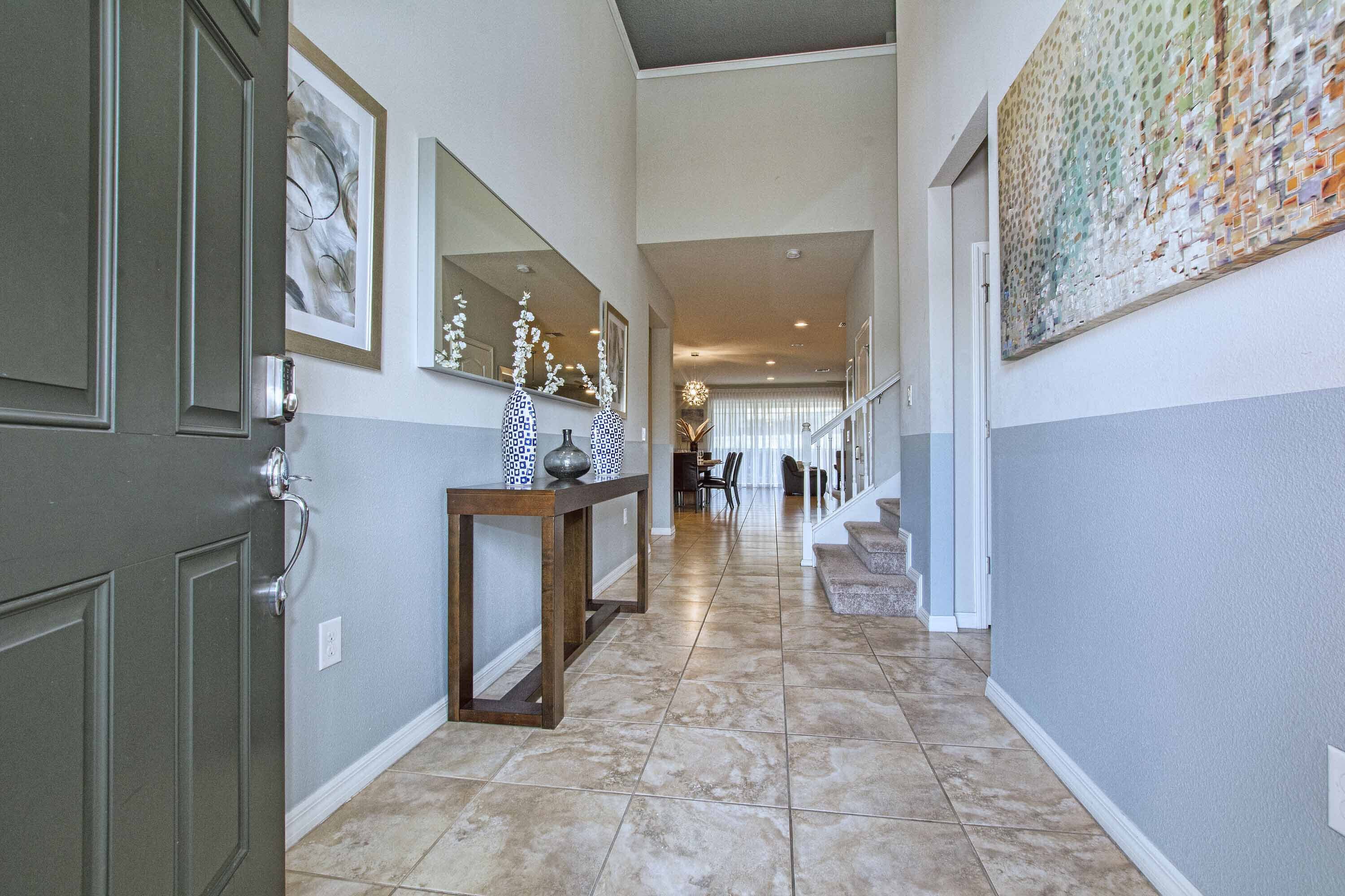 A hallway with a wooden console table, framed artwork, and a staircase leading to an upper level.