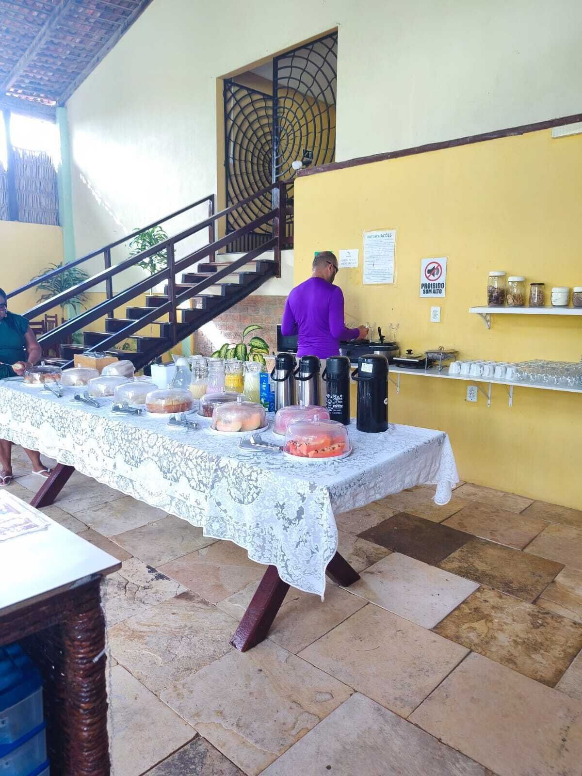 A buffet setup with a table covered in a lace tablecloth, food items, and a coffee station.