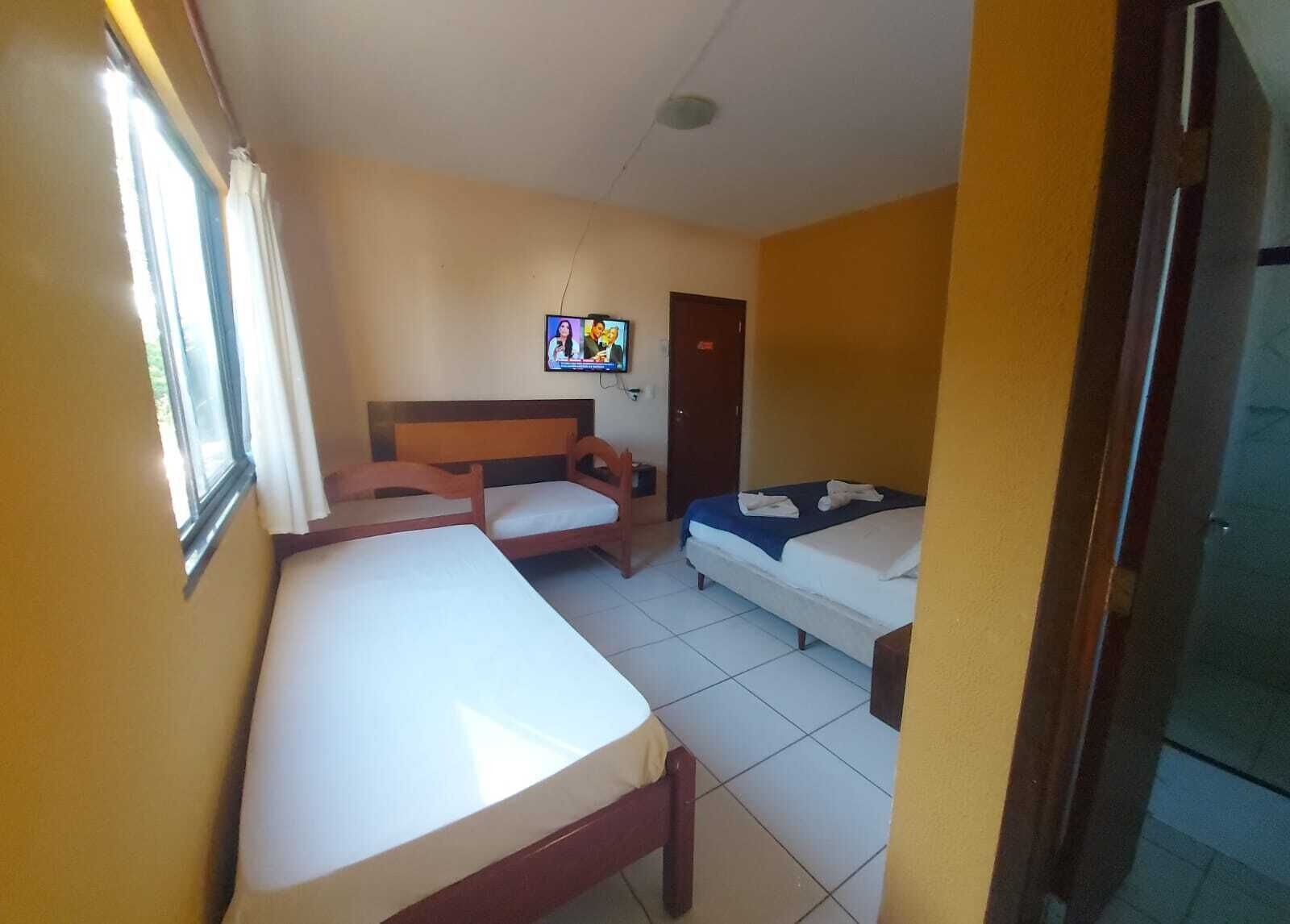 Una habitación de hotel con dos camas, un escritorio, una silla y un televisor en la pared.
