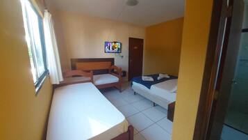Una habitación de hotel con dos camas, un escritorio, una silla y un televisor en la pared.