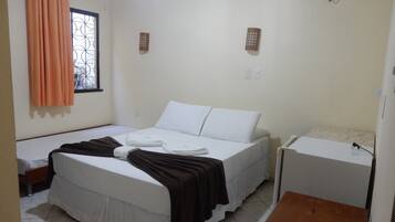 Una habitación con cama, mesita de noche, ventana con cortinas y un interruptor de luz en la pared.