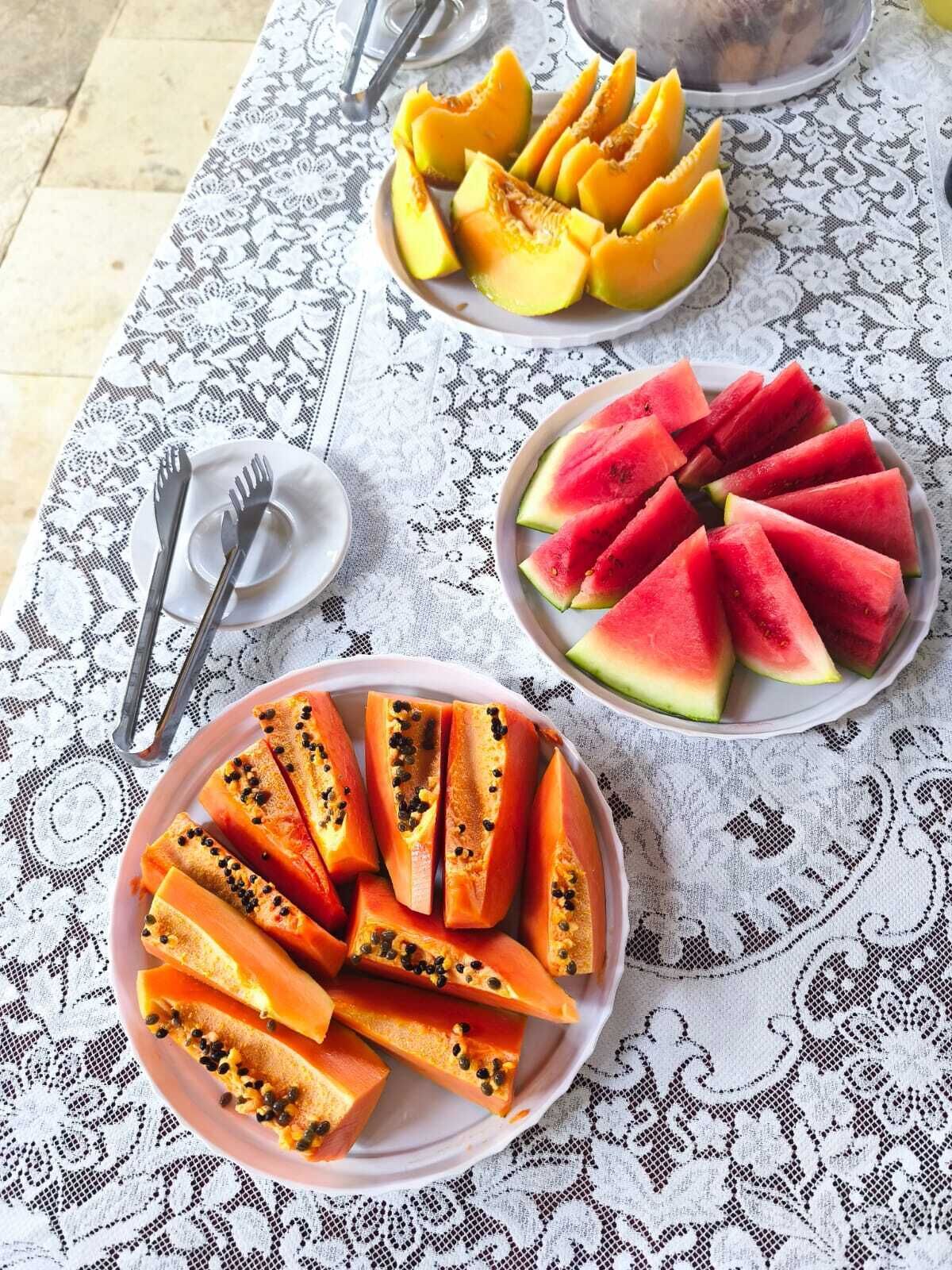 Una mesa con platos de frutas cortadas y cubiertos.