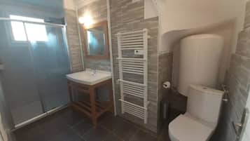 A bathroom with a shower, sink, toilet, and a towel rack.