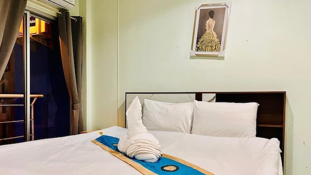 A neatly made bed with white linens, a blue towel, and a decorative pillow. - Blue Pearl Shore (Patong)