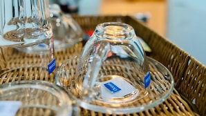A wicker tray with clear glass tumblers and a kettle in the background. - Blue Pearl Shore (Patong)