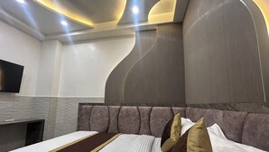 Een moderne hotelkamer met een groot bed, een flatscreen televisie aan de muur en een bijzonder plafondontwerp.