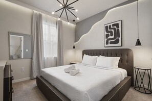 A modern hotel room with a large bed, a bedside table, a mirror, and a unique wall art piece. - Last Minute Disney Getaway! Luxury Villa with Private Pool. Book Now! #124659 (Orlando)