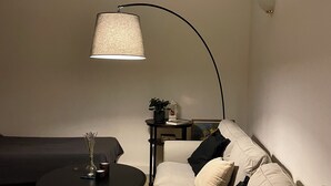 Una sala de estar con un sofá, una mesa de centro, una lámpara y una mesita auxiliar con una planta.