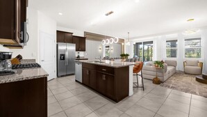 A modern kitchen with dark cabinets, a stainless steel refrigerator, and a central island.