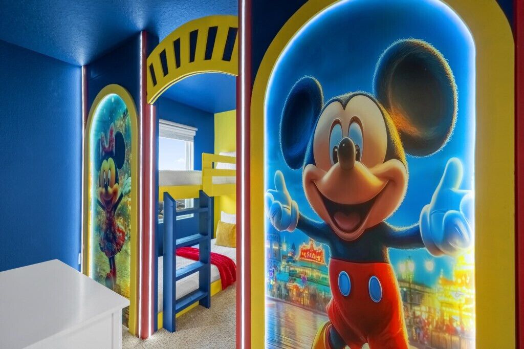 Habitación infantil con una cama litera, un mural de Mickey Mouse y un diseño de videojuego de colores en la pared.