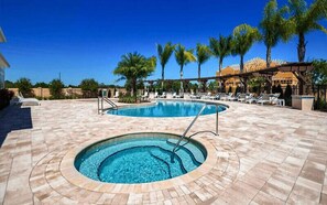 A swimming pool area with lounge chairs and palm trees.