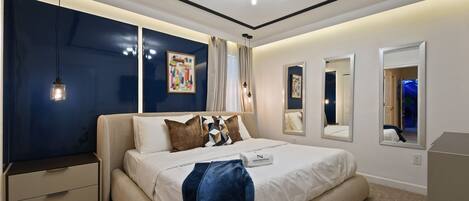 Un dormitorio moderno con una cama grande, una mesita de noche, un aparador y una lámpara en el techo.