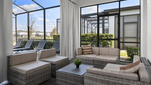 A modern outdoor seating area with wicker furniture and a glass enclosure. - Last Minute Disney! Private Pool, Hot Tub, Game Room & Themed Bedrooms. Book Now! #125865 (Orlando)
