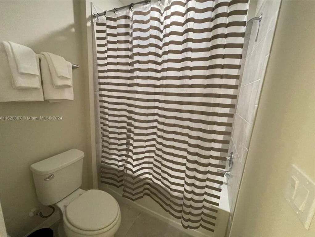 A bathroom with a striped shower curtain, a toilet, and a towel rack.