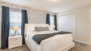 A bedroom with a bed, bedside tables, a lamp, and a patterned wall.