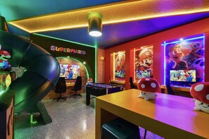 Quarto com mesa de futebol de mesa, parede com tema do Mario e placa com a inscrição Super Mario.