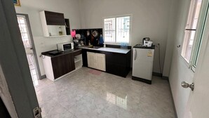 Una cocina compacta con encimera blanca, microondas, fregadero y refrigerador.