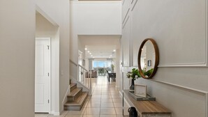 A modern interior with a staircase, a wooden console table, a mirror, and a framed picture. - Last Minute Disney! Private Pool, Hot Tub, Game Room & Themed Bedrooms. Book Now! #128641 (Orlando)