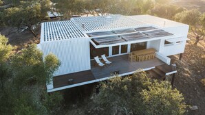 A modern house with a flat roof, large windows, and a deck with outdoor furniture. - Monte das Casolas (Grandola)